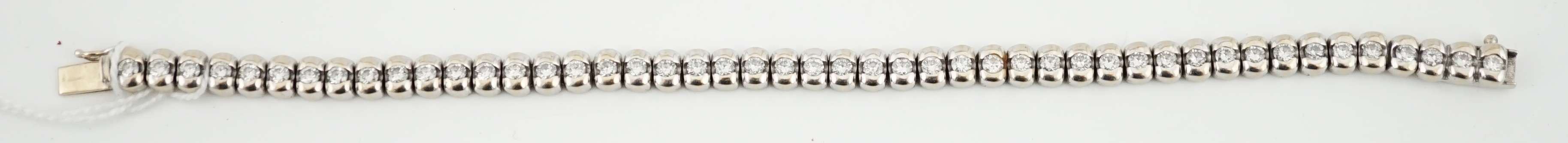 A modern 18ct white gold and collet set forty seven stone round brilliant cut diamond set line bracelet